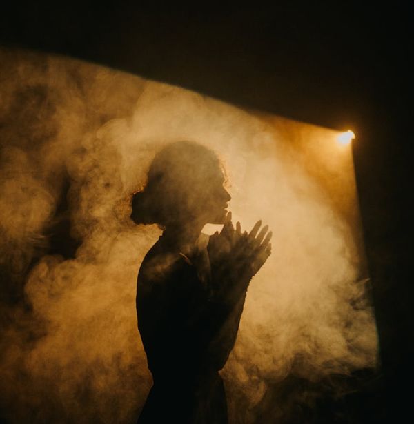 Atmospheric photo of a person meditating in a low-key light room.