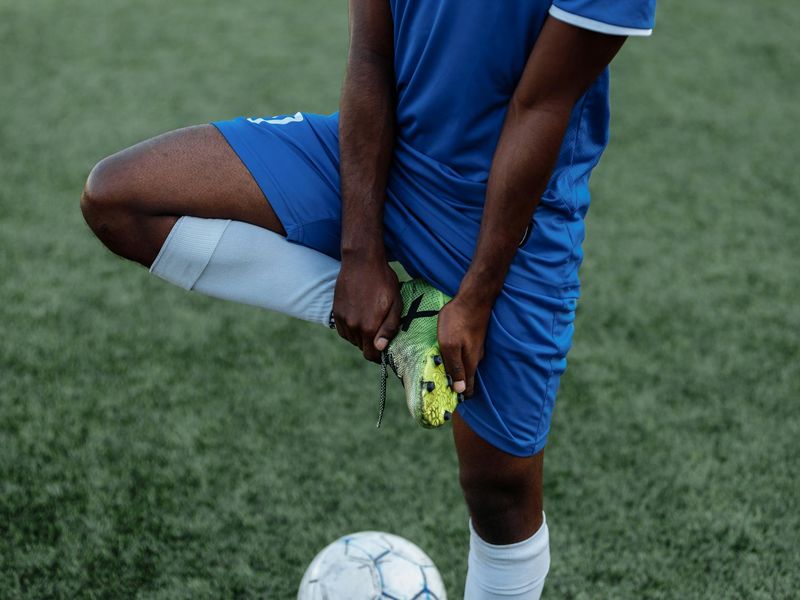 Detailed close-up of sports equipment and a person stretching in shadows.
