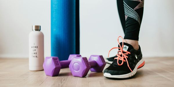 Minimalist arrangement of training mat and water bottle on dark floor.