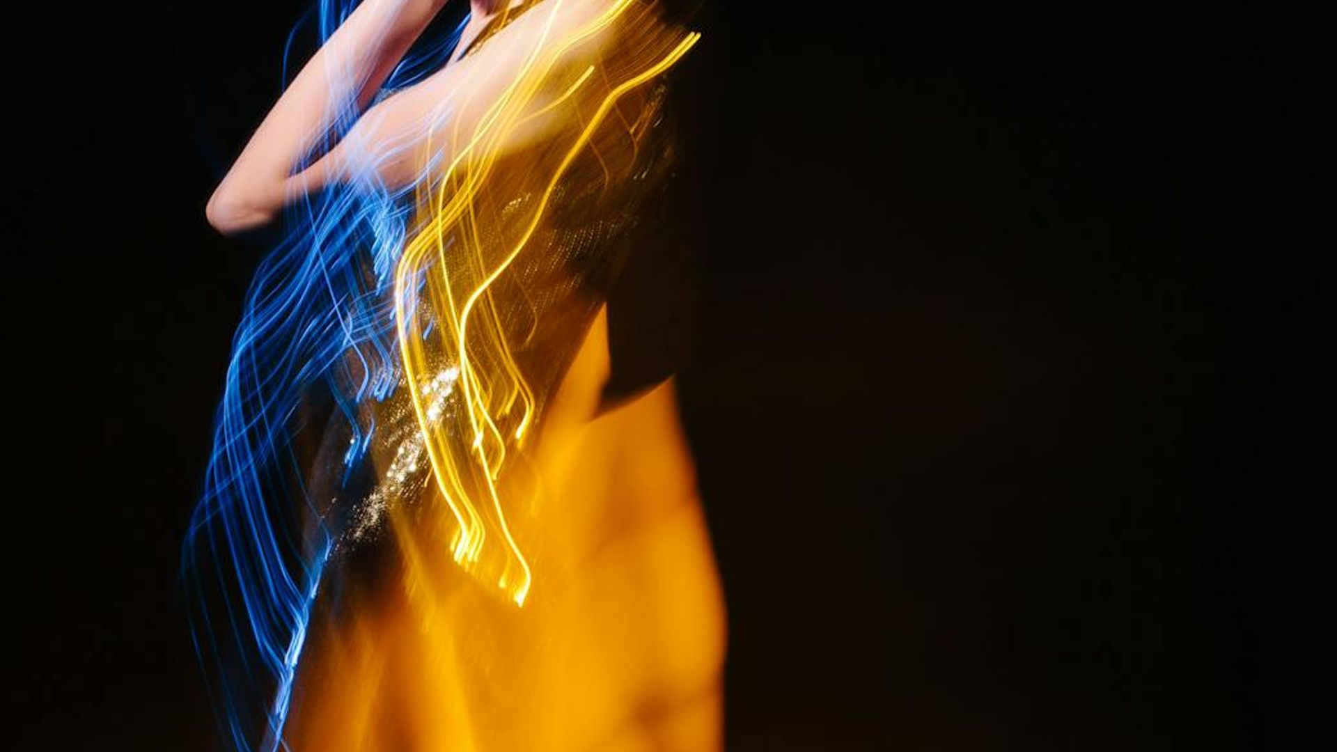 Person doing dynamic movements in a modern dark studio setting with blue light.